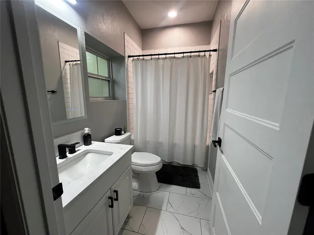 a bathroom with a sink a toilet a mirror and shower