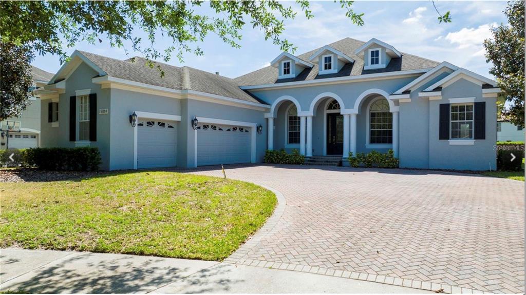 a view of a white house with large windows and a yard with a large tree