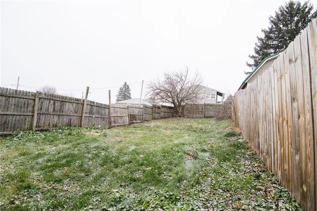 a view of a house with wooden fence and a large tree