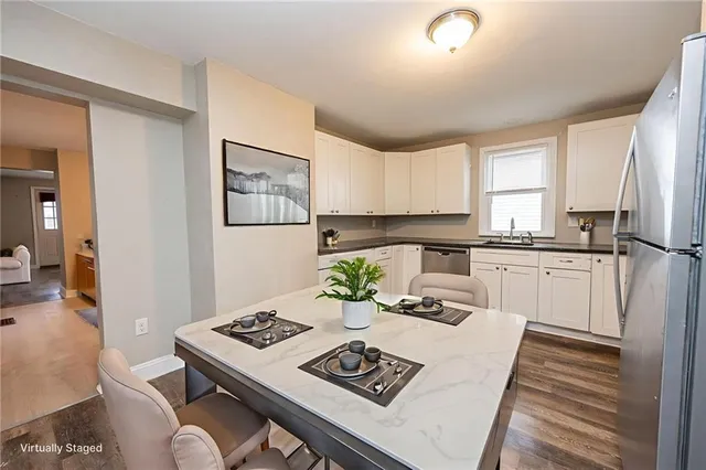 a kitchen with a refrigerator a stove a sink dishwasher and white cabinets with wooden floor