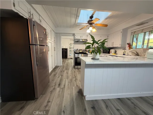 a kitchen with kitchen island stainless steel appliances a sink stove refrigerator and cabinets