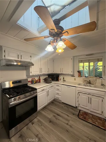 a kitchen with stainless steel appliances a stove a sink and white cabinets