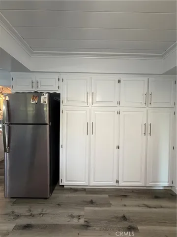a view of a refrigerator in kitchen and white cabinets