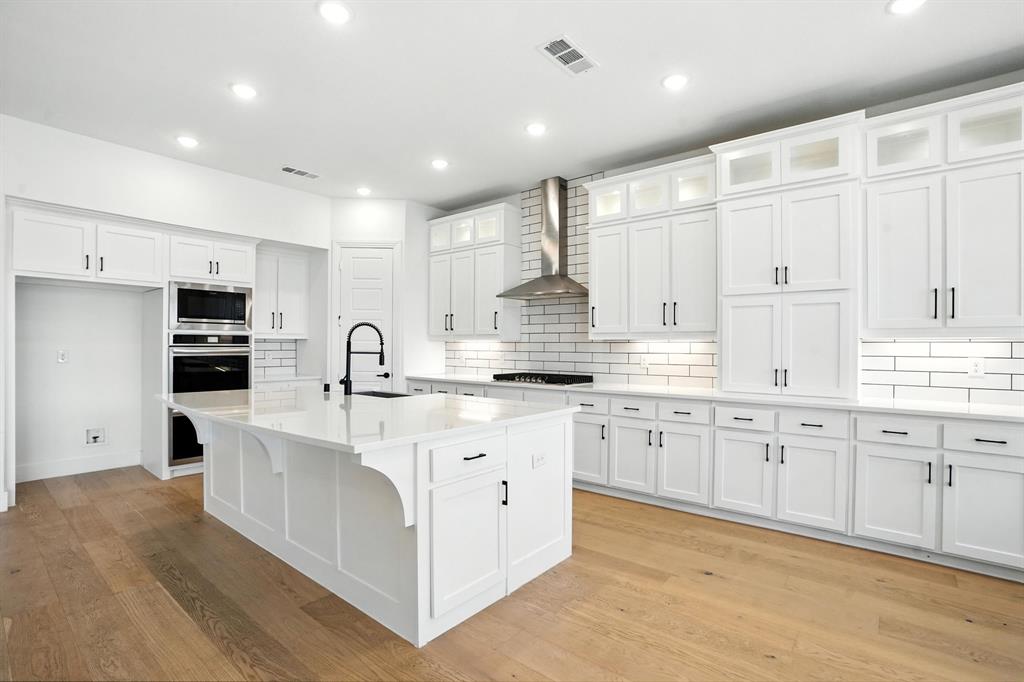 4621 Mount Vista Road Oak Point, TX 75068 - Photo 14 of 40 a large white kitchen with stainless steel appliances granite countertop a stove a sink a refrigerator and white cabinets with wooden floor
