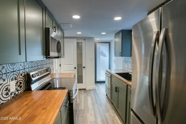 a kitchen with stainless steel appliances granite countertop a refrigerator a stove and a sink