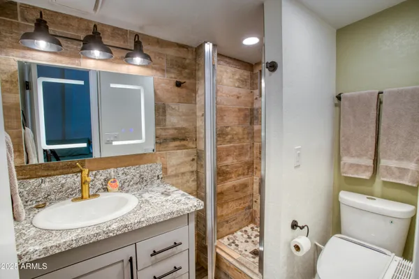a bathroom with a granite countertop sink toilet and shower