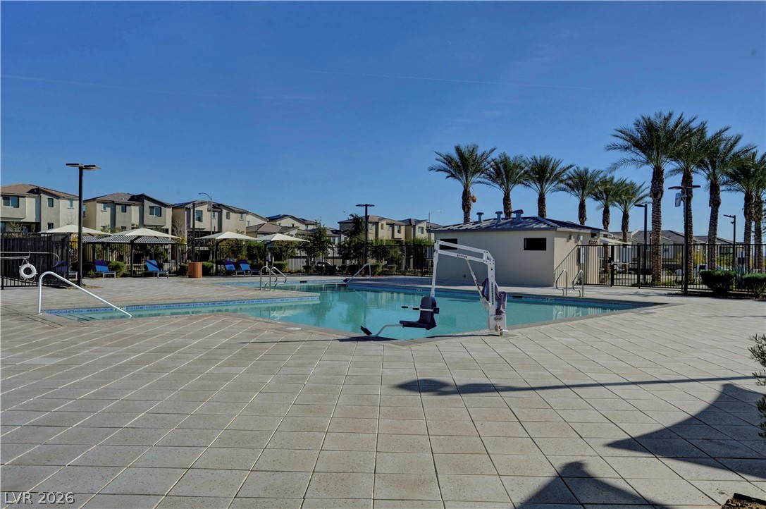 6924 Spicy Merlot Street North Las Vegas, NV 89086 - Photo 70 of 83 A refreshing pool area with ample lounging space, nestled among palm trees and residential structures.