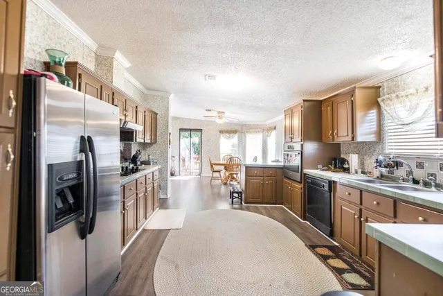 a kitchen with stainless steel appliances a refrigerator a sink a stove top oven a dining table and chairs with wooden floor