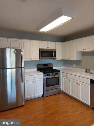 a kitchen with granite countertop a refrigerator stove top oven and sink