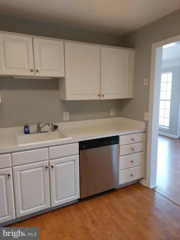 a kitchen with white cabinets and sink