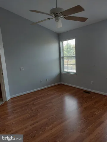 an empty room with wooden floor ceiling fan and windows