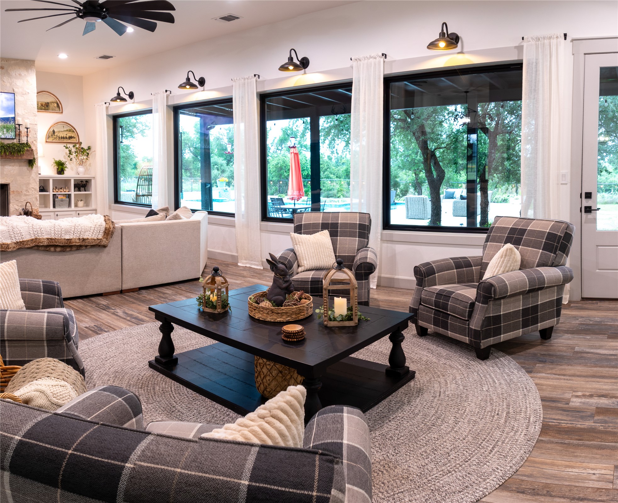 272 Slate Rock Road Fredericksburg, TX 78624 - Photo 13 of 32 Sun-filled living area features tile hardwood-look plank flooring and a statement ceiling fan, overlooks back patio and pool.