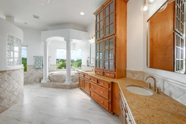 a large bathroom with a granite countertop tub a sink and a large window