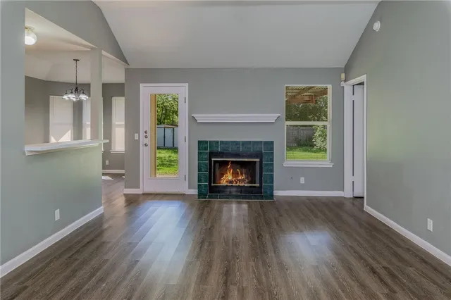 a view of an empty room with wooden floor fireplace and a window