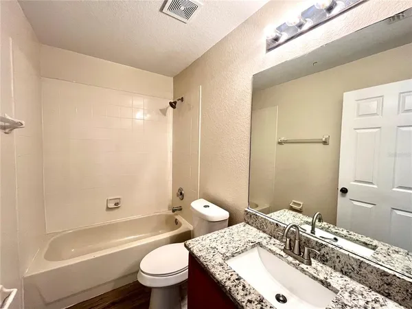 a bathroom with a granite countertop sink a toilet and shower