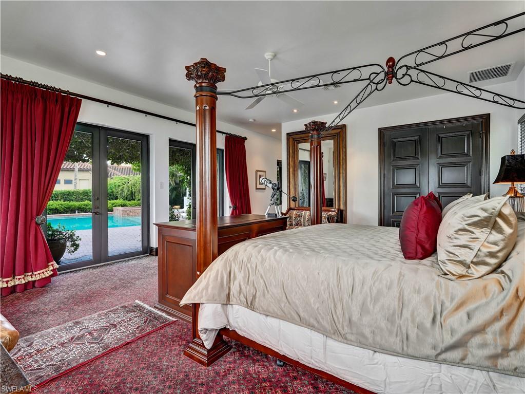 2535 Tarpon Road Naples, FL 34102 - Photo 20 of 50 Bedroom featuring a four-poster bed, red patterned carpet, and multiple windows