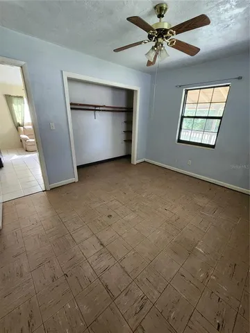 an empty room with windows and ceiling fan