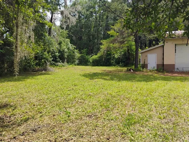 a view of a yard with a house and large trees
