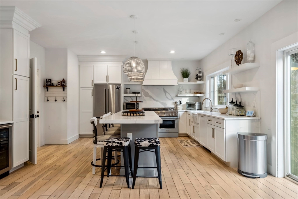 58 Folly Mill Road Salisbury, MA 01952 - Photo 3 of 31 a kitchen with stainless steel appliances kitchen island granite countertop a wooden floor and white cabinets