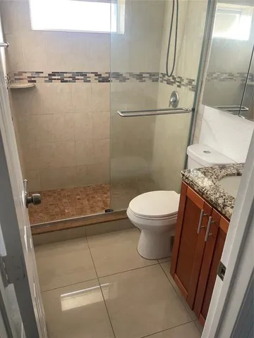 a bathroom with a granite countertop sink toilet and shower