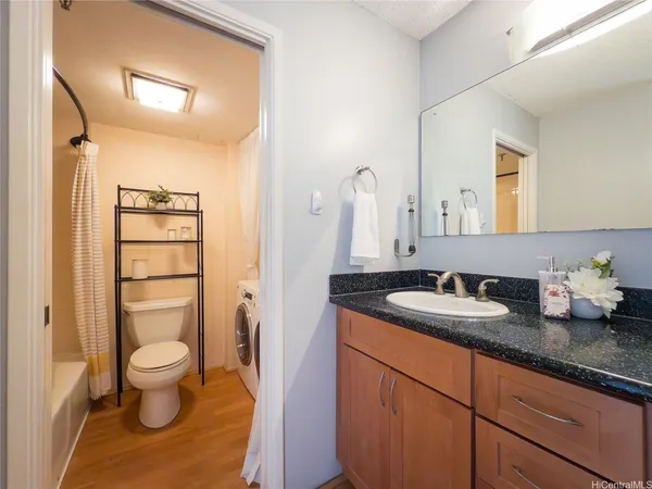 a bathroom with a granite countertop sink mirror vanity and toilet