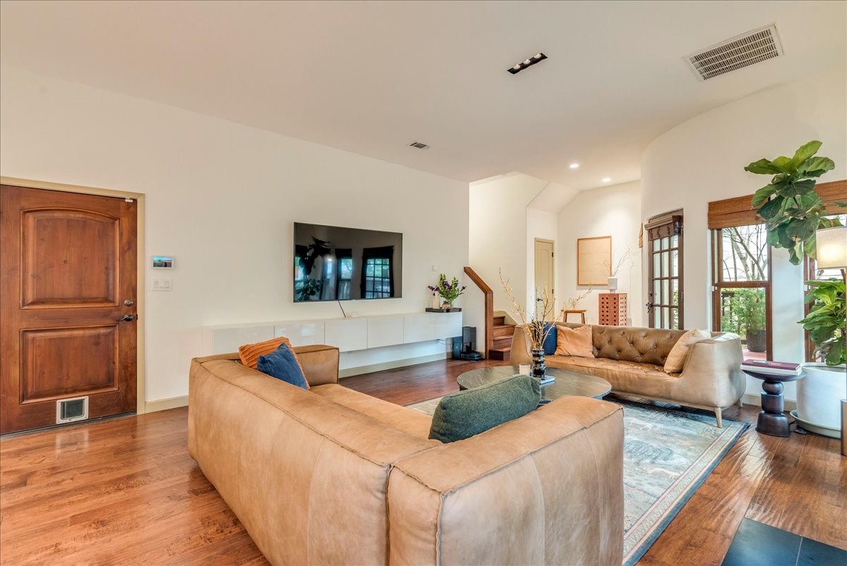 3012 South 4th Street, Unit B Austin, TX 78704 - Photo 5 of 40 Spacious living area featuring polished wood-finish flooring, white walls, and a multi-pane door with a sidelight