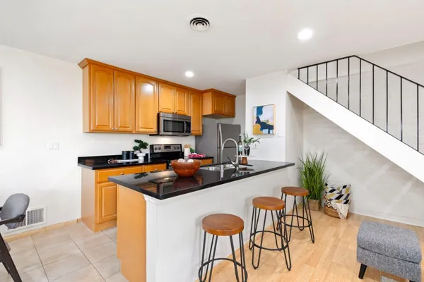 a kitchen with granite countertop a table chairs stove a sink dishwasher and cabinets with wooden floor