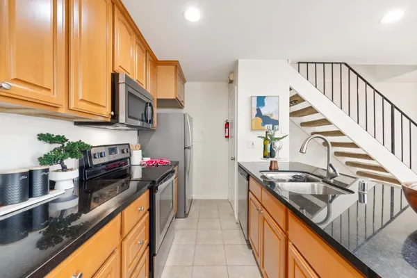 a kitchen with stainless steel appliances granite countertop a sink a stove and a wooden cabinets
