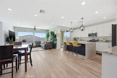 a living room with stainless steel appliances kitchen island granite countertop furniture wooden floor and a view of kitchen