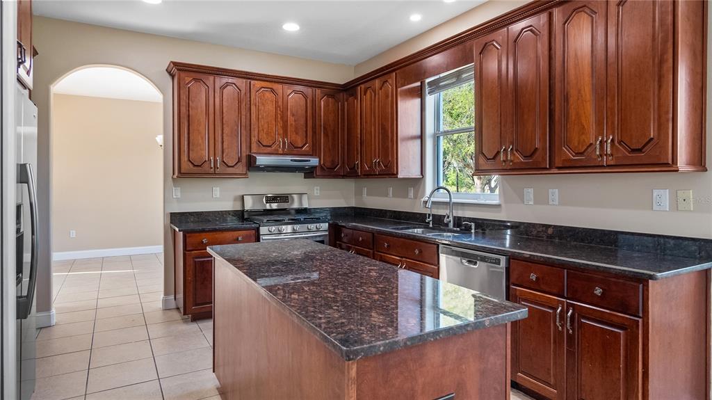 10651 Arrowtree Boulevard Clermont, FL 34715 - Photo 19 of 51 a kitchen with stainless steel appliances granite countertop wooden cabinets a stove top oven a sink and dishwasher