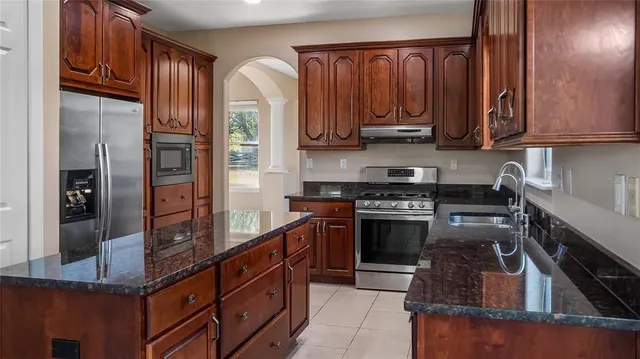 a open kitchen with stainless steel appliances granite countertop a refrigerator and a sink