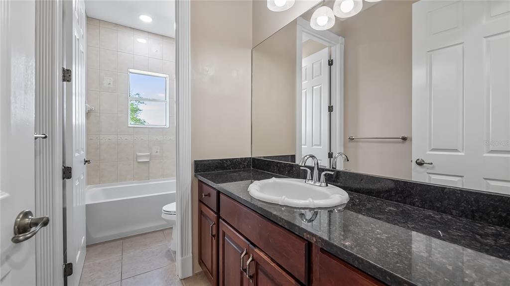 10651 Arrowtree Boulevard Clermont, FL 34715 - Photo 34 of 51 a bathroom with a granite countertop sink and a mirror a bathtub