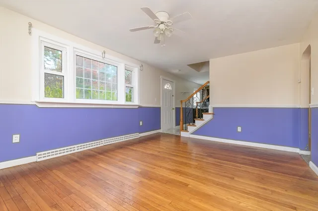a view of an empty room with window and wooden floor
