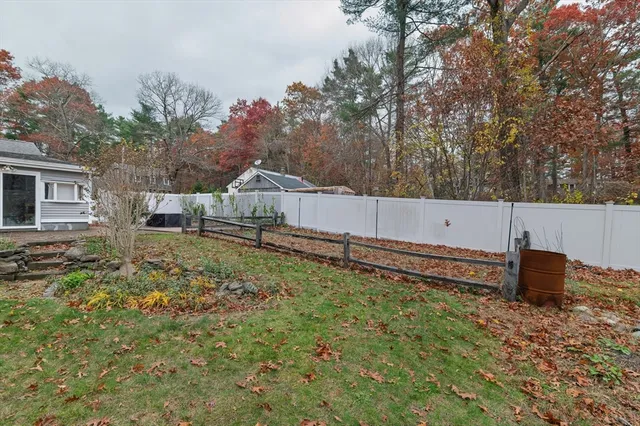 a backyard of a house with wooden fence and large trees