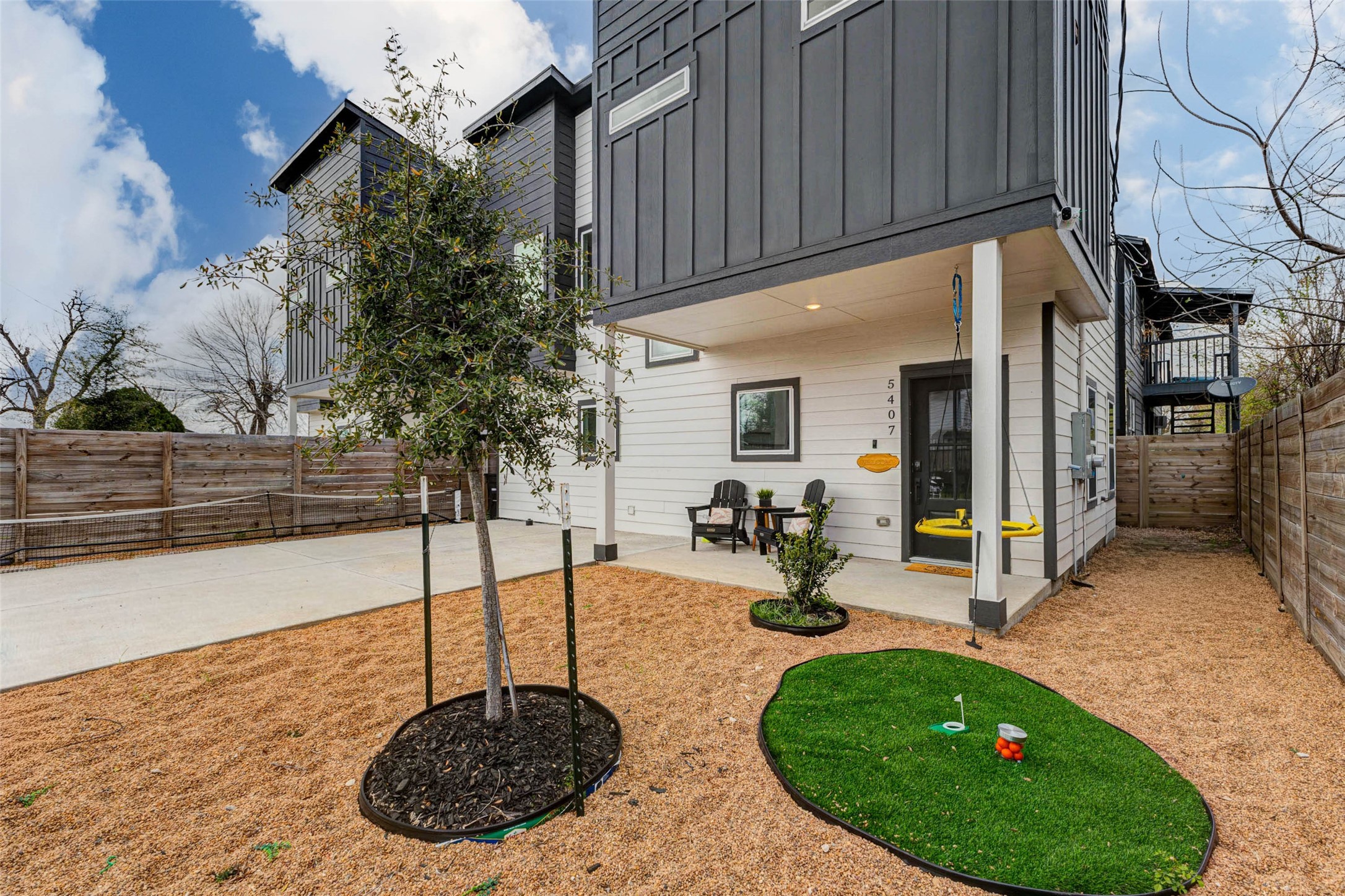 5407 Lee Street Houston, TX 77020 - Photo 2 of 17 Modern two-story home with a sleek exterior, featuring a low-maintenance yard. The backyard includes a small putting green, patio seating, and a swing. Ideal for outdoor relaxation and entertaining.