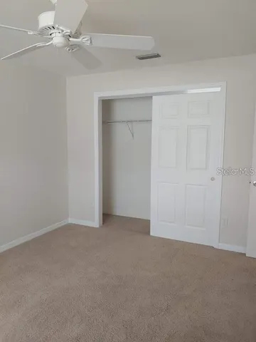 an empty room with a ceiling fan and closet area