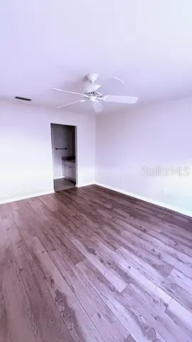 a view of empty room with wooden floor and fan
