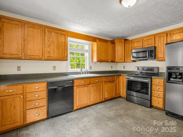 a kitchen with stainless steel appliances granite countertop a stove a sink and a microwave
