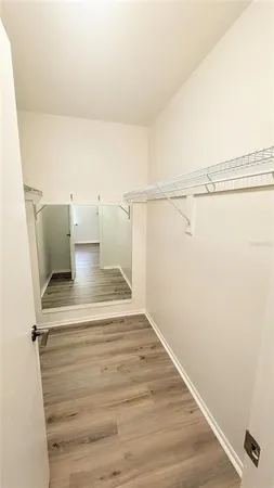 an empty room with wooden floor chandelier fan and windows