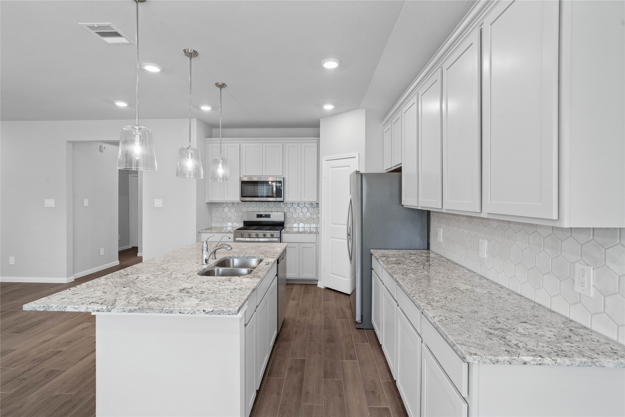 19645 Montgomery Rdg Way Montgomery, TX 77316 - Photo 13 of 41 Discover this chef-ready kitchen featuring sleek, shaker-style white cabinetry, Andino White granite countertops, and a full suite of stainless steel appliances, including an over-the-range microwave and a side-by-side refrigerator.