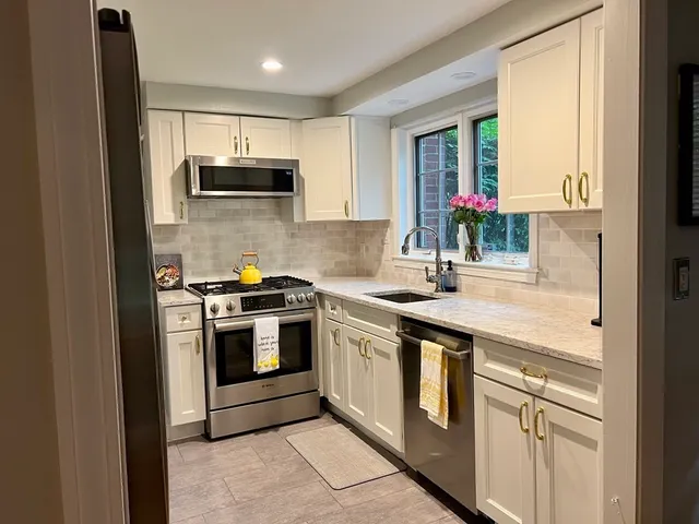 a kitchen with granite countertop a sink stainless steel appliances and cabinets