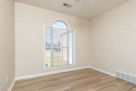 an empty room with wooden floor and window