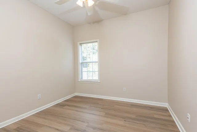 an empty room with wooden floor chandelier fan and window