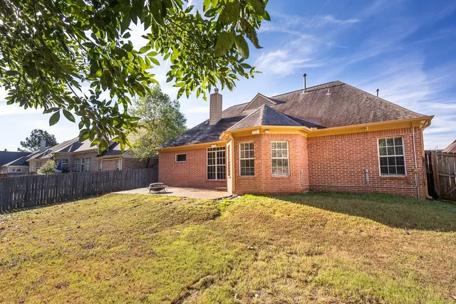 a front view of house with yard and trees in the background