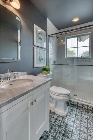 a bathroom with a granite countertop toilet a sink and a window