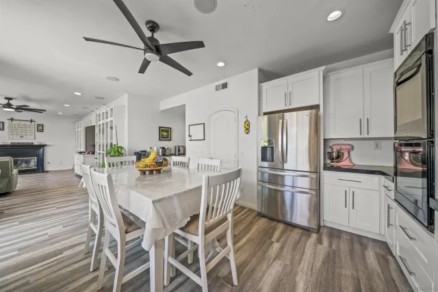 a kitchen with stainless steel appliances a dining table chairs and wooden floor