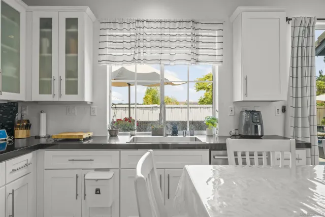 a kitchen with stainless steel appliances kitchen island granite countertop a table chairs refrigerator and sink