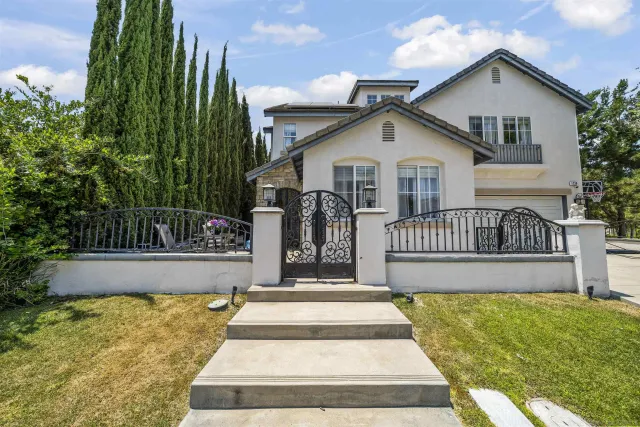 a view of a house with a small yard plants and large tree