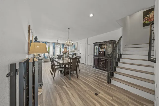 a kitchen with stainless steel appliances kitchen island granite countertop a refrigerator a stove a sink with island chairs and wooden floor