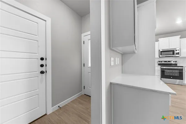 a view of a hallway with wooden floor and a bathroom